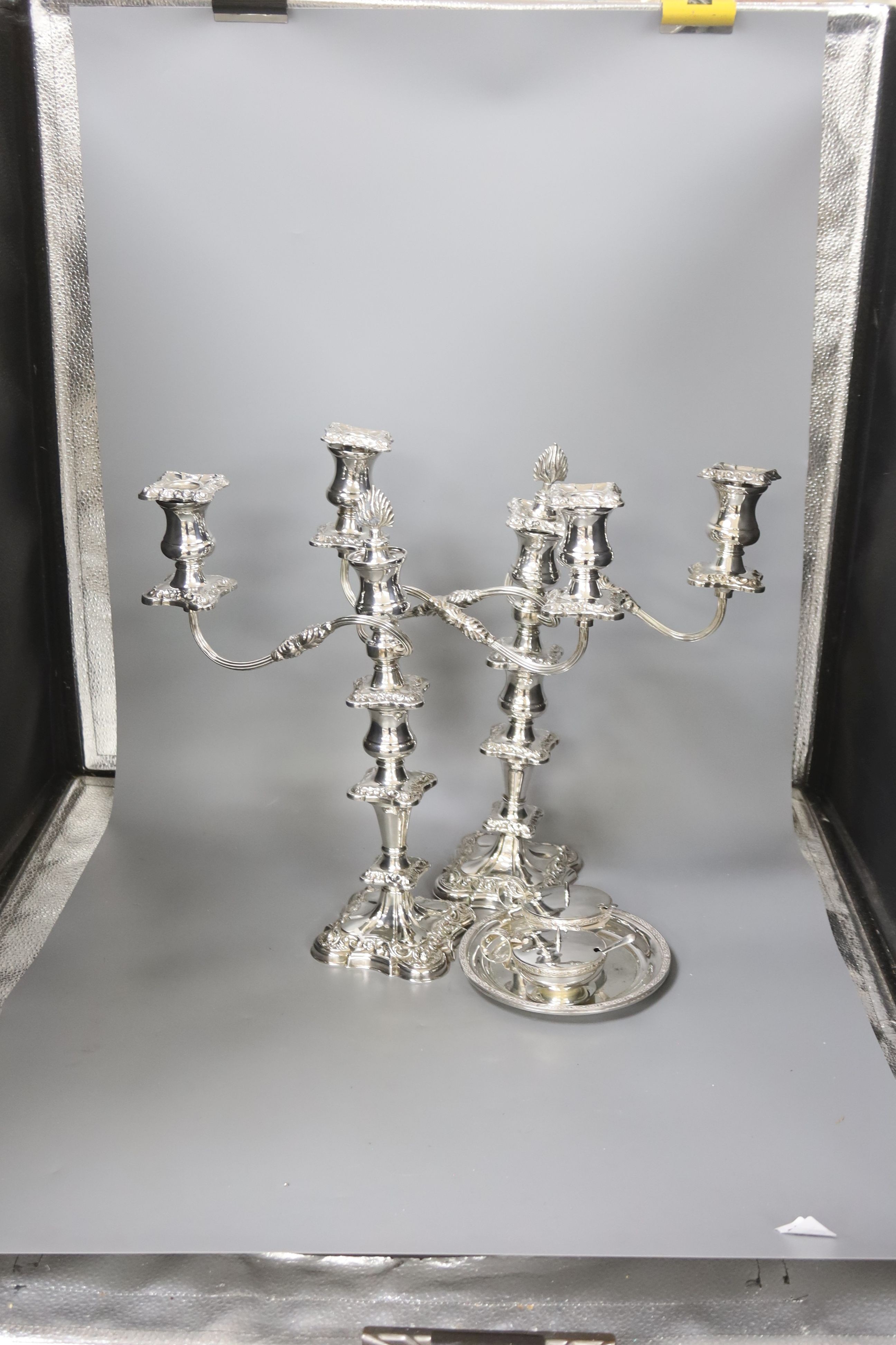 A pair of silver plated candelabra, two plated salvers and two plated mustard pots